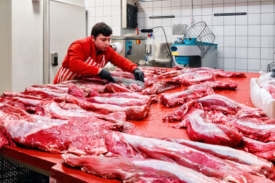 屠夫或切肉者在屠宰场或屠宰场准备生牛犊肉