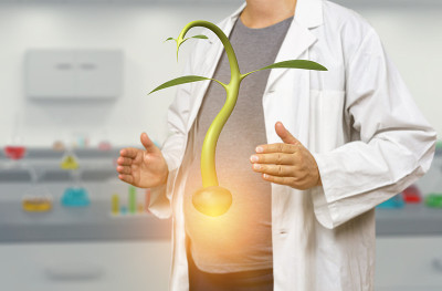 怀孕的白人女科学家拿着发芽的种子在一个模糊的实验室背景