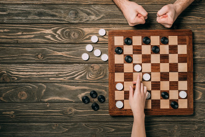 男人和女人在木背景下玩跳棋的裁剪观点