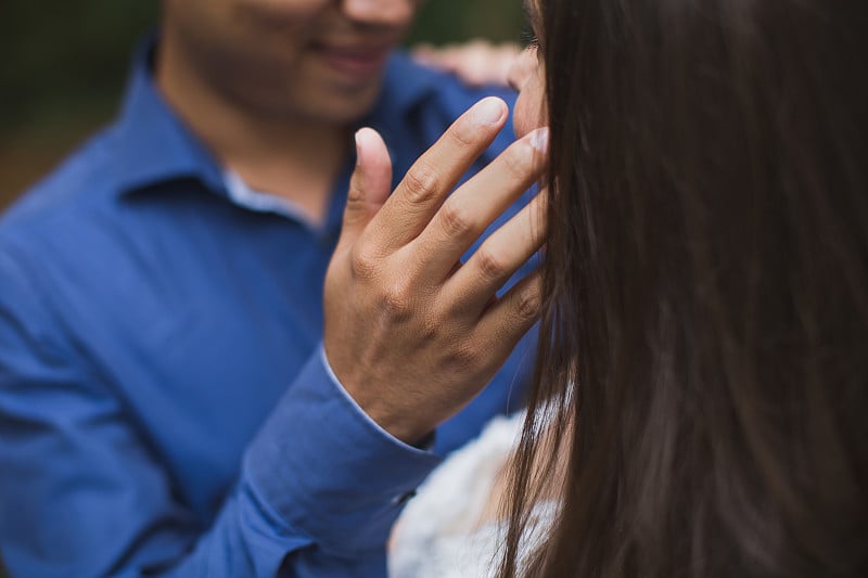 婚礼当天，新郎新娘在绿色背景的树林里接吻