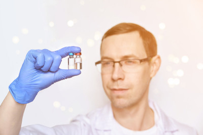 Hand in glove hold vaccine. Man face