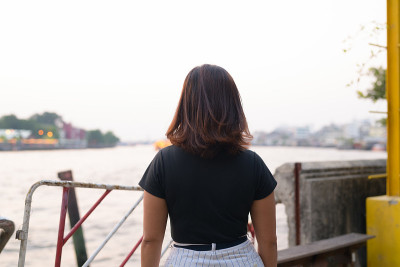 年轻的亚洲女游客在河边码头的后视图