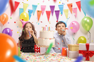 一个小女孩和一个小男孩吹着派对喇叭庆祝生日
