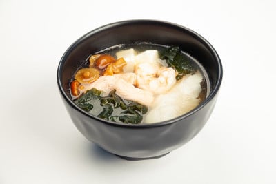 味增汤与海鲜在一个黑色卡雷卡。配料:肉汤、虾、鲑鱼、鲈鱼、豆腐芝士、名子菇、味噌酱、宏鱼、裙带菜。对
