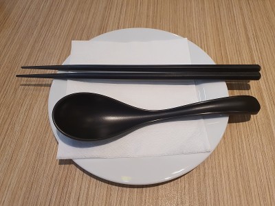 勺子和筷子放在白色盘子里，放在木桌上