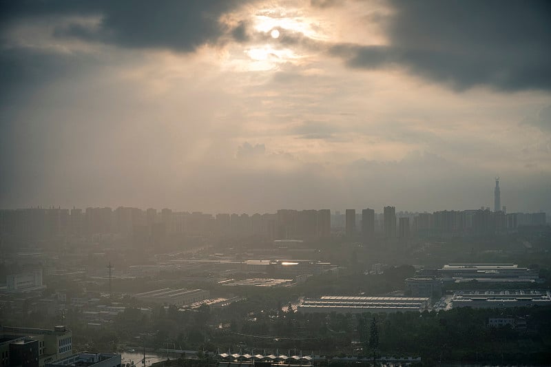 太阳在雨中穿过云层形成潮汐效应的城市
