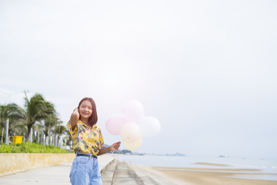 亚洲年轻女孩喜欢在海滩上玩气球。