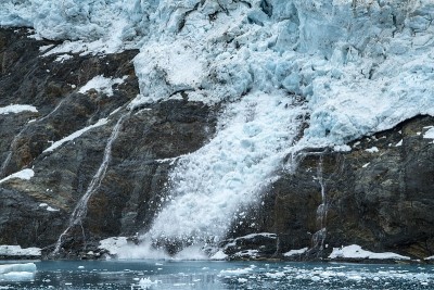 冰川上松散的积雪滑过岩石斜坡进入海洋