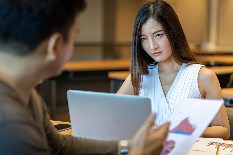 愤怒的老板斥责亚洲年轻女商人在现代办公室的绩效和KPI，商业错误和惩罚的概念