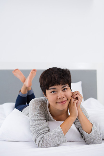 满意的亚洲女孩休息在舒适的床上