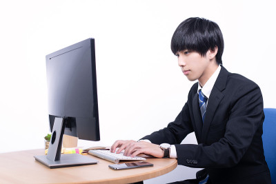 在台式电脑上工作的男性办公室职员。