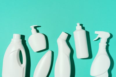 蓝色背景上的白色塑料瓶、化学清洁产品容器的图案。前视图。平的。停止塑料、回收、分门别类收集垃圾的概念