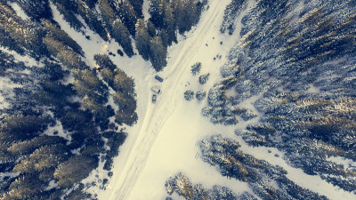 鸟瞰图的积雪覆盖的道路通过森林。