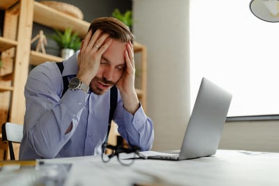 在他的办公室里，紧张的男建筑师双手抱头坐在桌子旁。