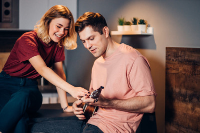 young woman teaching man play ukulele