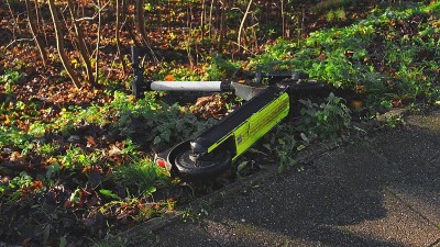 掉落的公共共享城市电动车被遗弃在路边的草地和灌木丛中