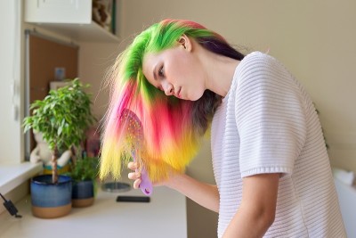 时尚少女用时髦的彩虹染发在家梳头发