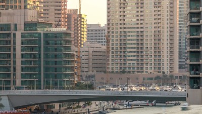 在迪拜滨海区，游客乘坐的游艇和船只停留在购物中心附近，并从桥下经过