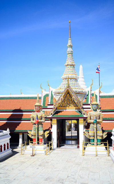 在泰国曼谷的翡翠佛寺，两尊巨大的守护雕像矗立在泰国建筑门前。