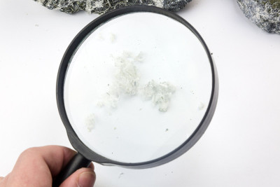 手用放大镜检查石头中的石棉纤维