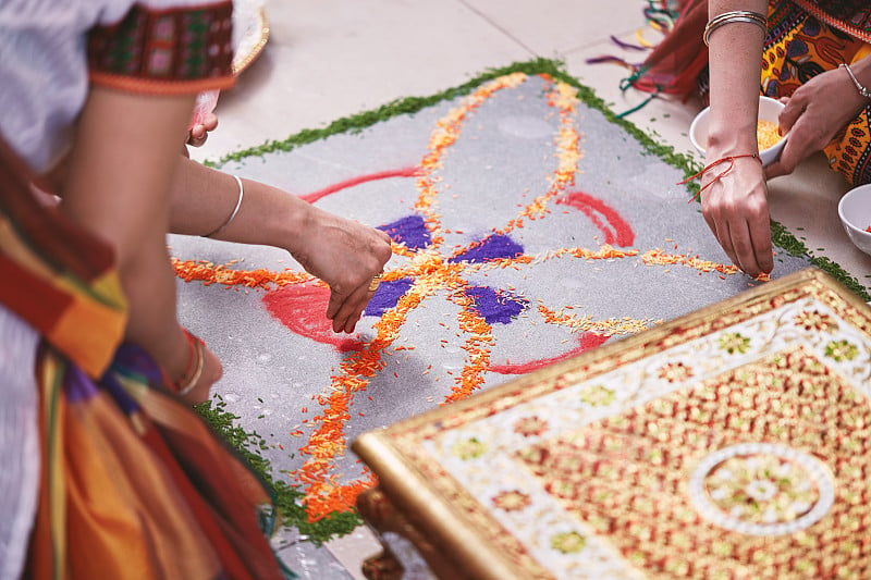 在印度的婚礼上，妇女们帮助在地板上给传统的大米艺术(Rangoli)上色