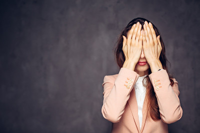 一个白人女人在深色背景上遮住眼睛