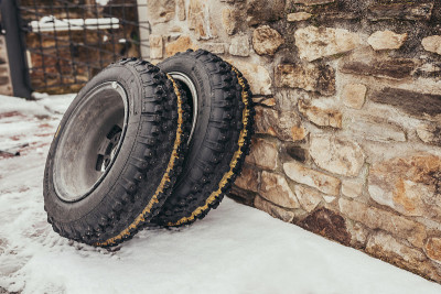 在下雪的冬天，钉满铆钉的轮胎靠在石墙上