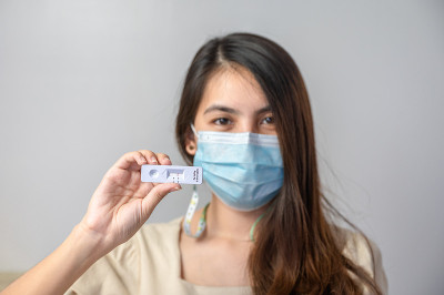 亚洲妇女戴口罩家庭使用快速抗原检测试剂盒结果阴性