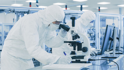 在实验室科学家穿着防护服做研究，使用显微镜和记录数据。工人在一个现代制造生产半导体和药品。