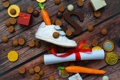 荷兰节日的Sinterklaas背景有儿童鞋、胡萝卜为圣诞老人的马、礼物、传统的蜜饯和巧克力信。平铺