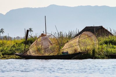 缅甸茵莱湖上，渔民腿上划着小船。