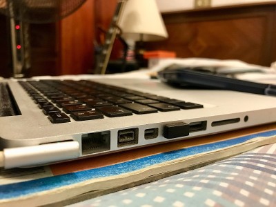 一个银色金属笔记本电脑的侧视图在一个绘图笔记本在床上