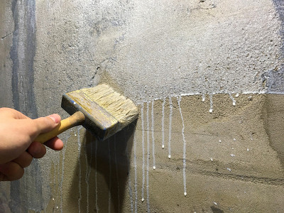 混凝土底漆工艺封闭。工人戴着手套，用刷子刷一堵混凝土墙