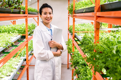 穿着白大褂的年轻成功女性研究员或农学家站在过道里