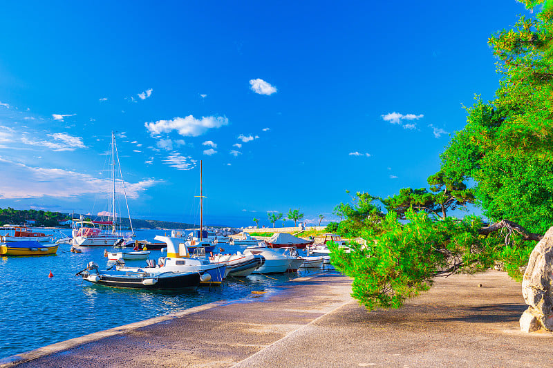 美妙浪漫的夏夜景观全景海岸线亚得里亚海。船和游艇停泊在清澈湛蓝的港湾里。克尔克岛的克尔克古城。克罗地