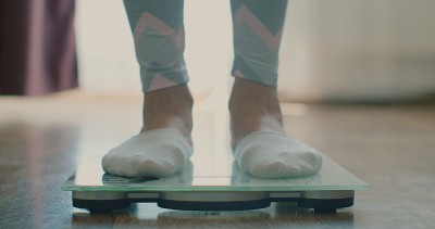 一个女人在家里用秤称体重的特写。一个女人的脚在秤上的特写。