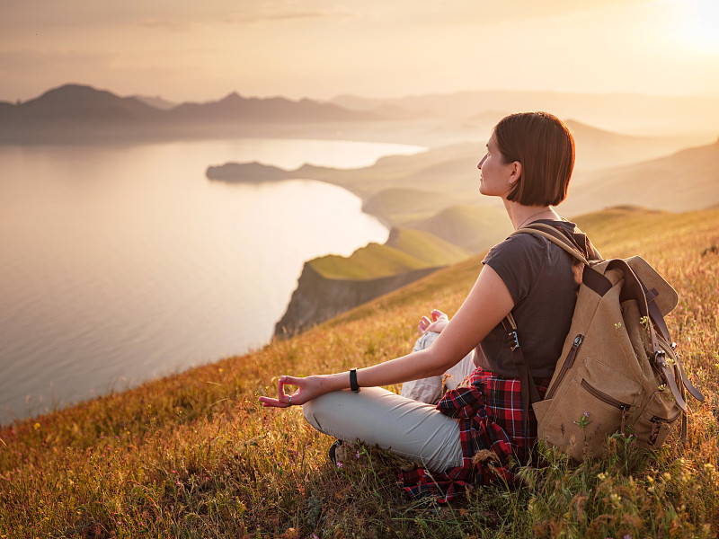 一个年轻的亚洲女人背着背包在夏天徒步旅行。