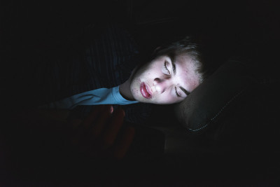 抑郁的少年在黑暗中玩手机。