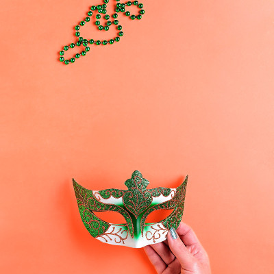 狂欢节饰品平铺在亮黄色的背景上，俯视图，复制空间。框架上有传统的狂欢节珠子，面具，扁平的羽毛。嘉年华