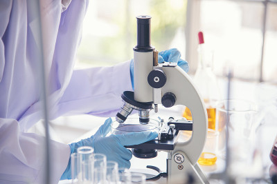 特写女科学家手用滴管在实验室看科学显微镜医学试验，研究生物化学。女性技术员实验室分析血液科学药物研究