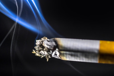 在黑色的背景下吸着烟灰的香烟