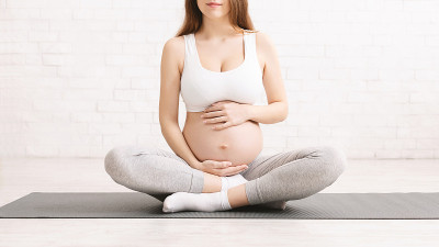 孕妇穿着运动服坐在瑜伽垫上