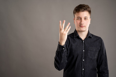 一幅严肃的、时髦的、有吸引力的男人的肖像，他穿着一件休闲的黑色衬衫，上面写着“4号”