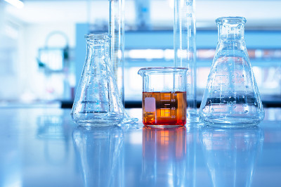 化学科学教育用的带橙色溶液的玻璃烧杯、圆筒和烧瓶，蓝色实验室背景