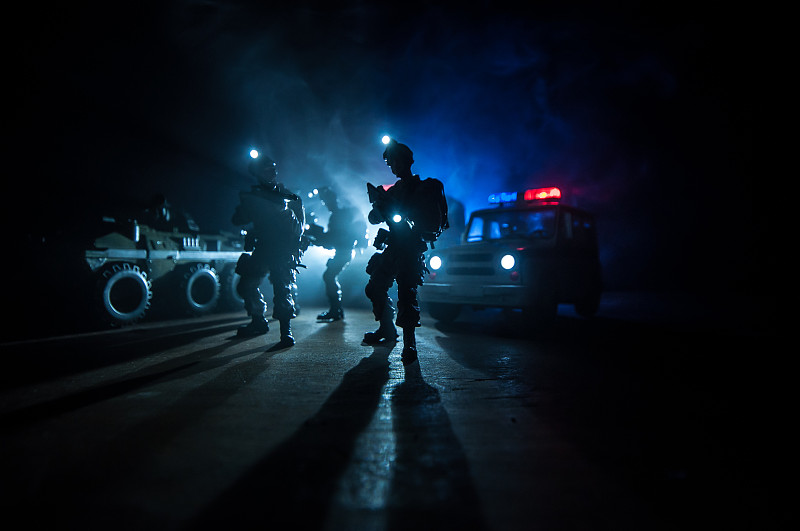 防暴警察发出了准备就绪的信号。政府权力的概念。警方在行动。烟雾在黑暗的背景与灯光。蓝红闪烁的警笛。独