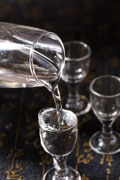烈酒或烈性酒是从一个瓶子的背景倒进玻璃杯