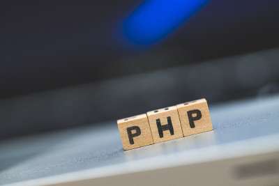 PHP编程网络语言:字母“PHP”的木制立方体躺在笔记本电脑上，概念