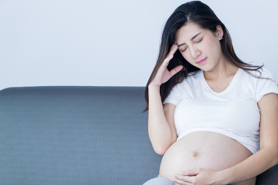美丽的年轻孕妇肖像与头痛和疼痛。怀孕保健为婴儿概念做准备。少女母亲的母性情感。