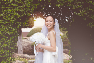 美丽迷人的亚洲新娘穿着婚纱，手捧花束微笑和幸福的婚礼