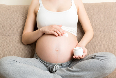 孕妇在腹部涂抹妊娠纹霜。怀孕，人与孕的观念。孕妇在腹部涂抹抗妊娠纹霜